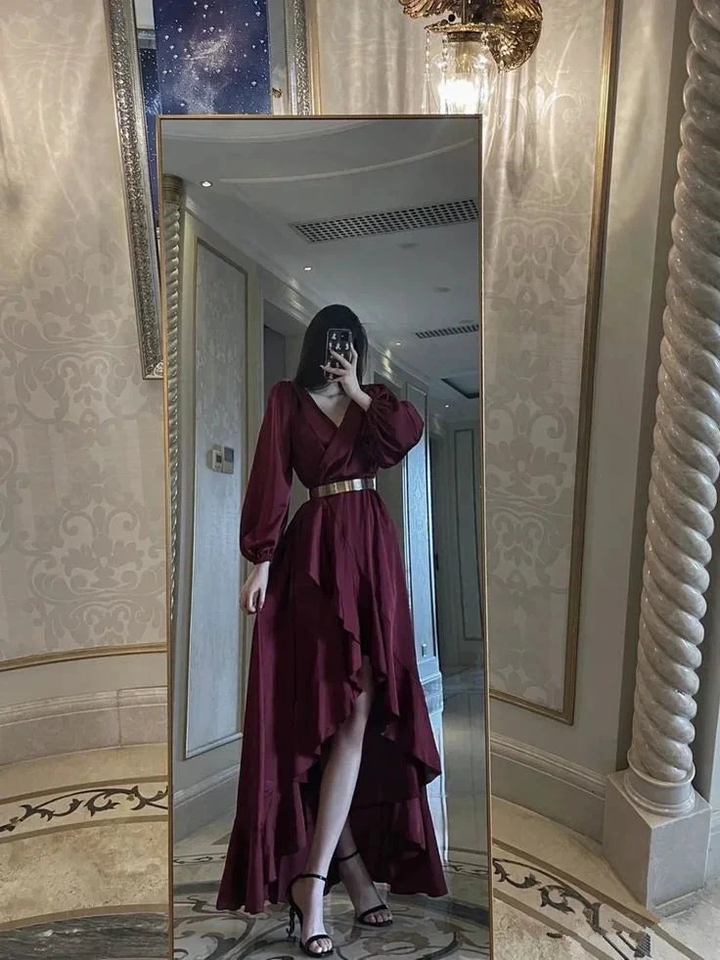 Woman in burgundy high-low dress with gold belt posing in luxurious hallway mirror for ZAPDRESS
