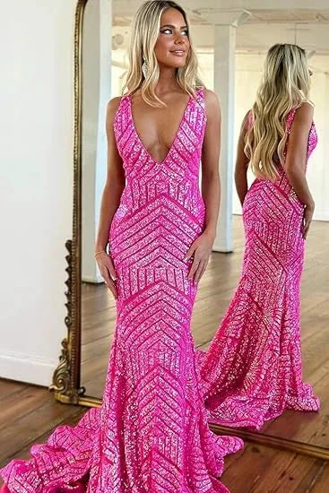 Woman in a vibrant pink sequin evening gown posing by a mirror on hardwood floor