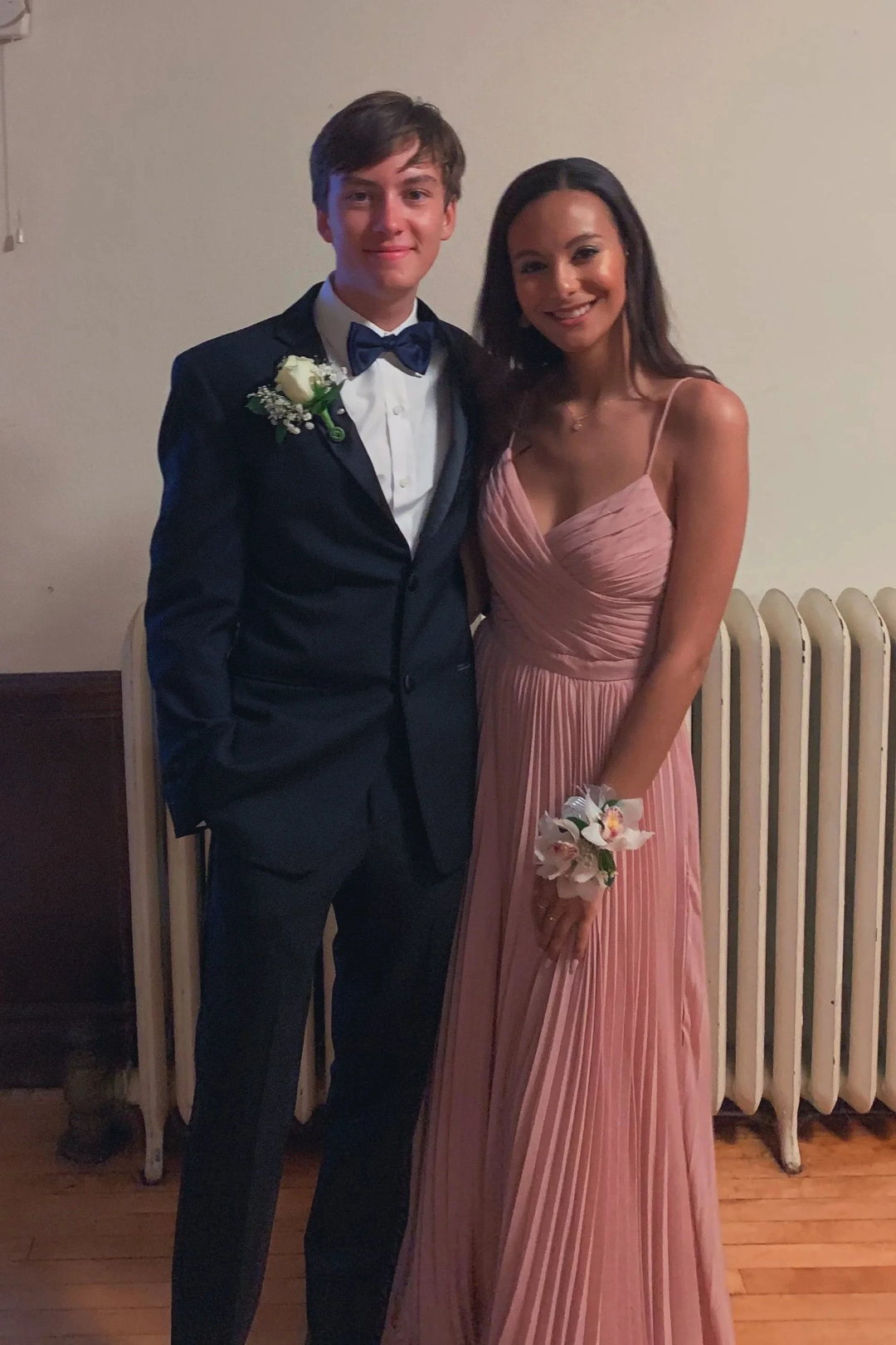 Young couple dressed for formal event, man in black tuxedo and woman in pink pleated gown