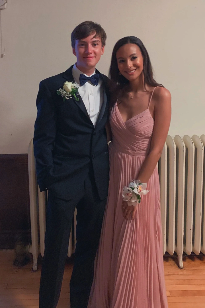 Young couple dressed for formal event, man in black tuxedo and woman in pink pleated gown