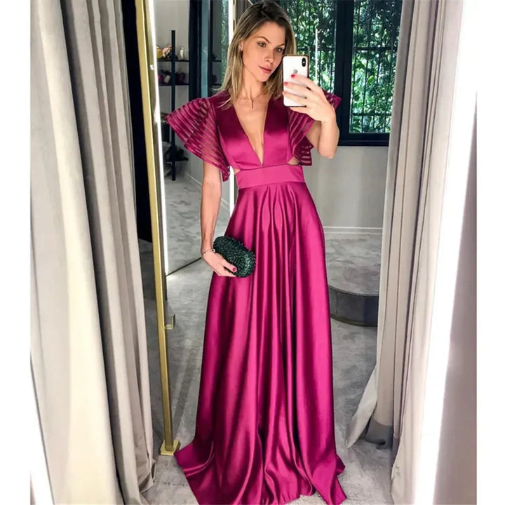Woman taking mirror selfie wearing a fuchsia satin evening gown in a modern room
