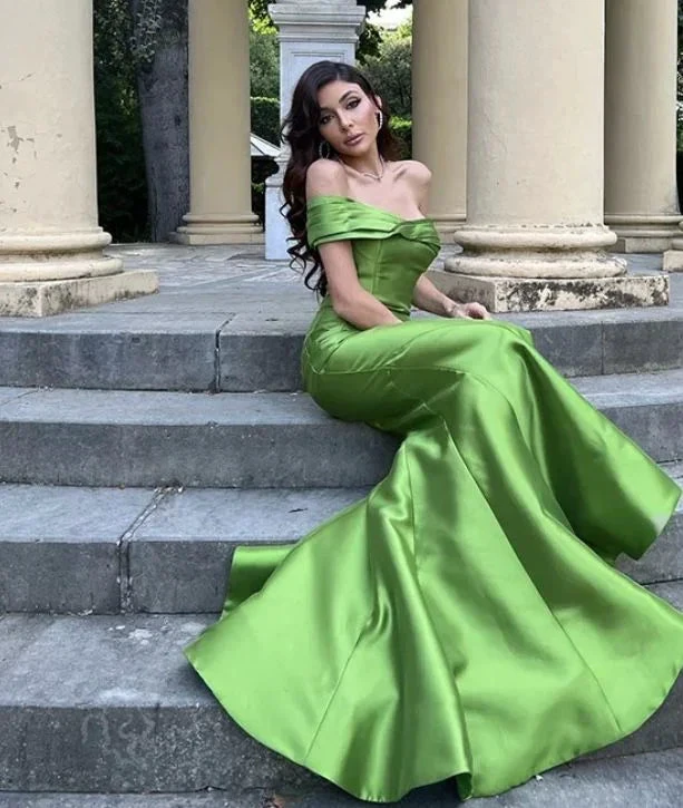 Woman in elegant off-shoulder green satin evening gown sitting on steps, ZAPDRESS fashion
