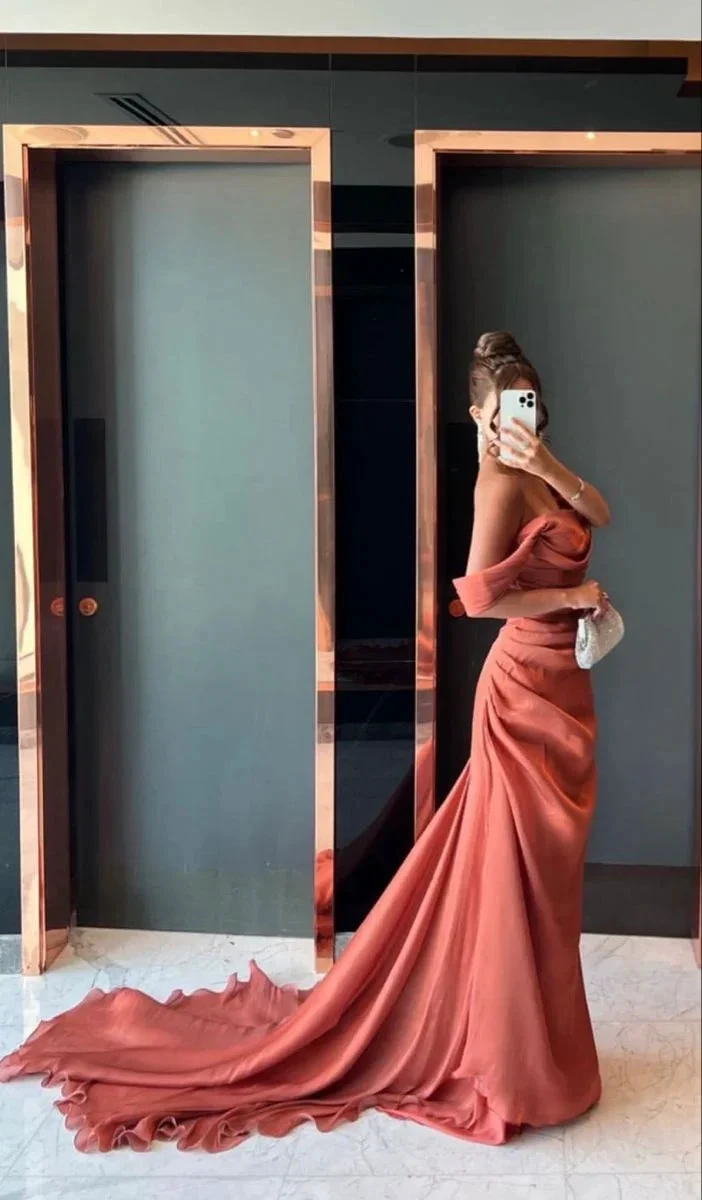 Woman in elegant off-shoulder coral gown with train posing in front of mirrored doors, ZAPDRESS