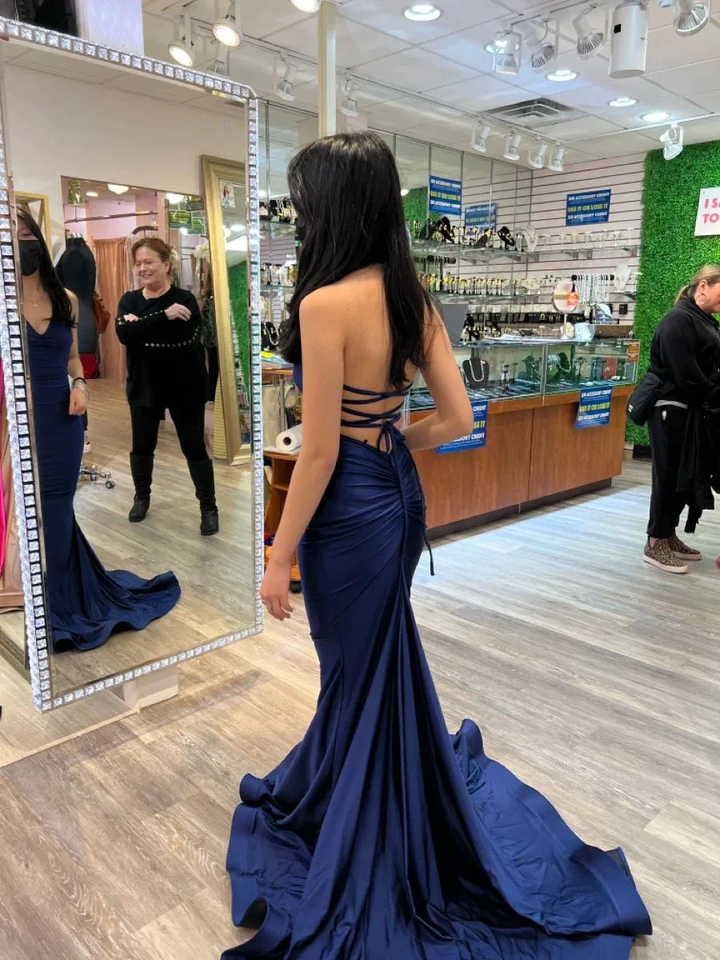 Woman wearing a navy blue backless gown in a boutique, looking in a mirror at ZAPDRESS