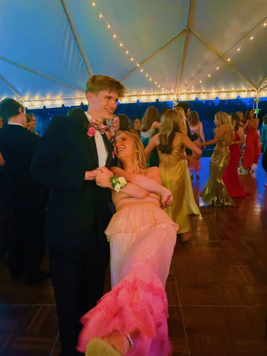 Teens dancing at a formal event under string lights, girl in pink ruffle dress from ZAPDRESS