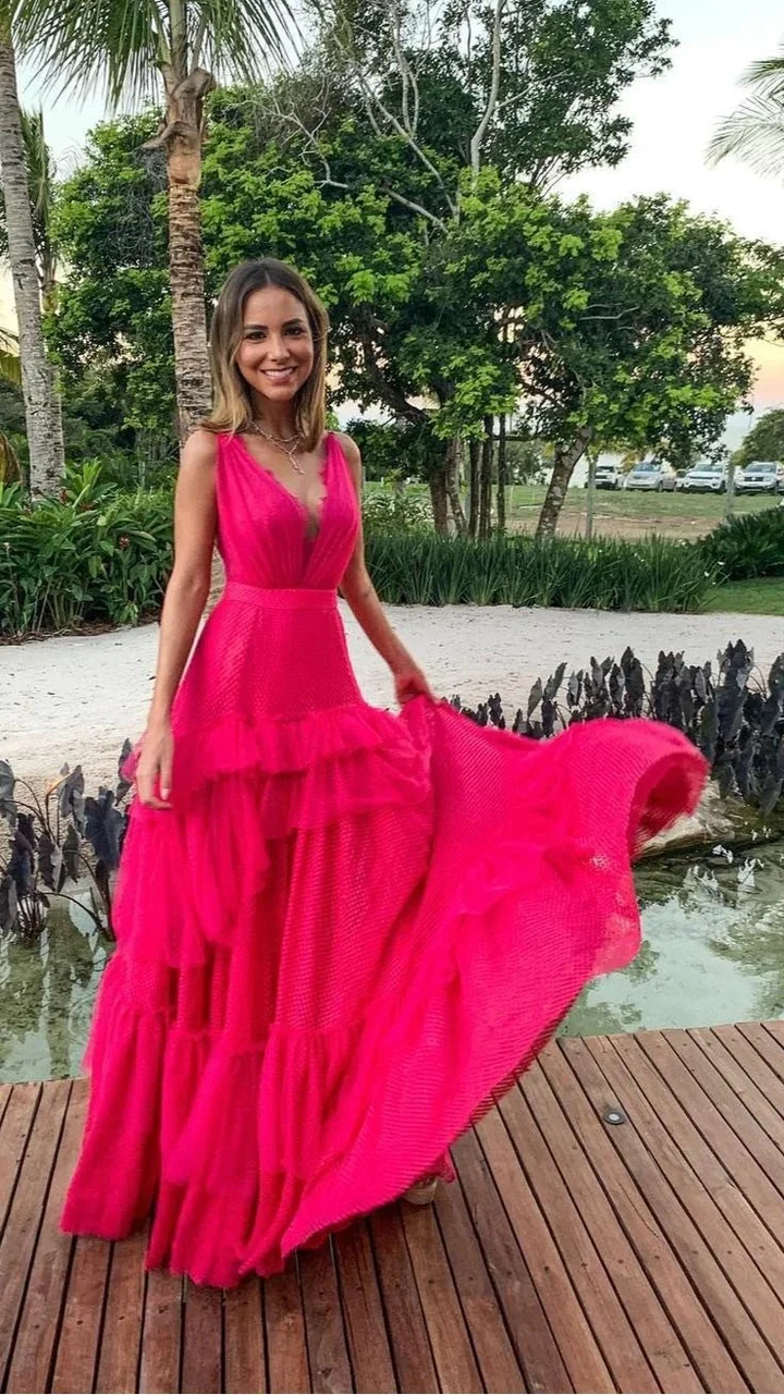 Woman in vibrant pink ruffled maxi dress standing outdoors on wood deck at ZAPDRESS