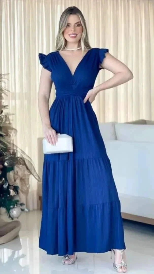 Woman in a blue maxi dress from ZAPDRESS holding a white clutch, standing indoors
