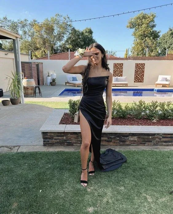 Woman in a black evening dress with thigh-high slit, standing by a pool in a modern backyard