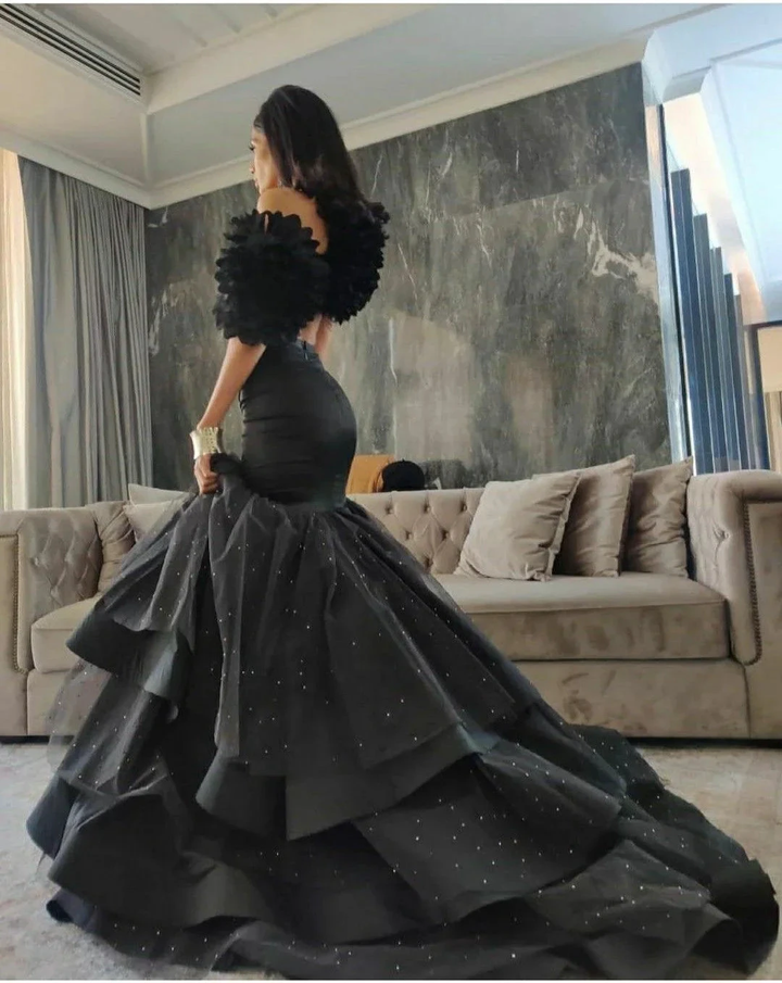 Woman wearing elegant black ruffled evening gown in luxurious living room, ZAPDRESS fashion