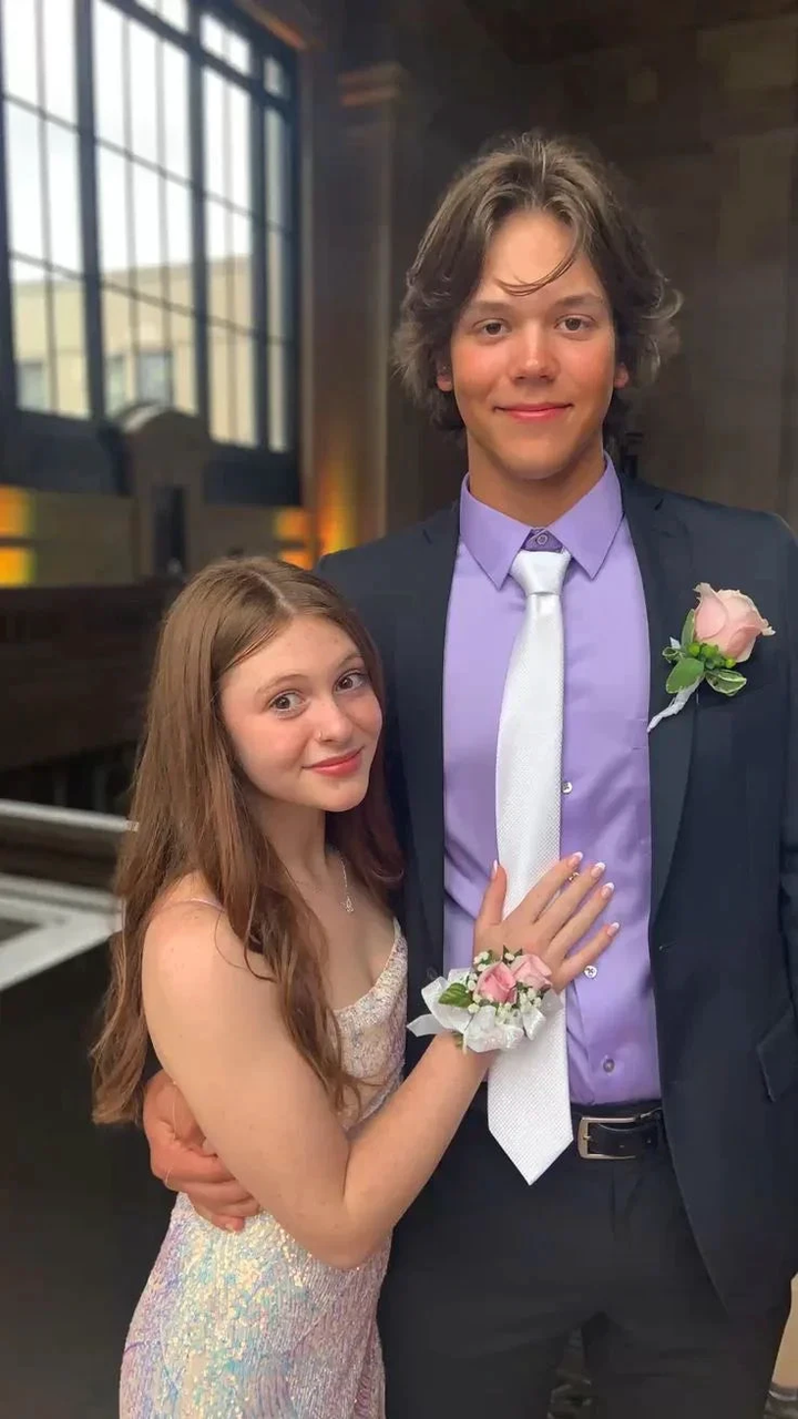 Young couple in formal attire for prom, girl in sparkly dress, boy in suit with lavender shirt, pink rose corsage, indoor elegant setting, ZAPDRESS