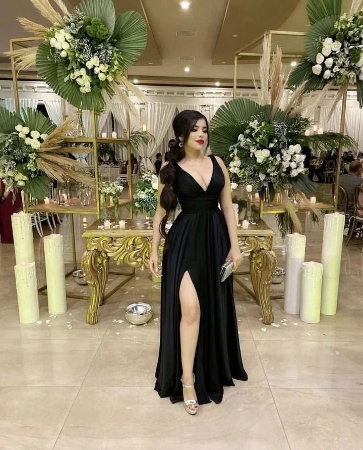 Woman in elegant black evening dress with thigh-high slit at a decorated event, ZAPDRESS