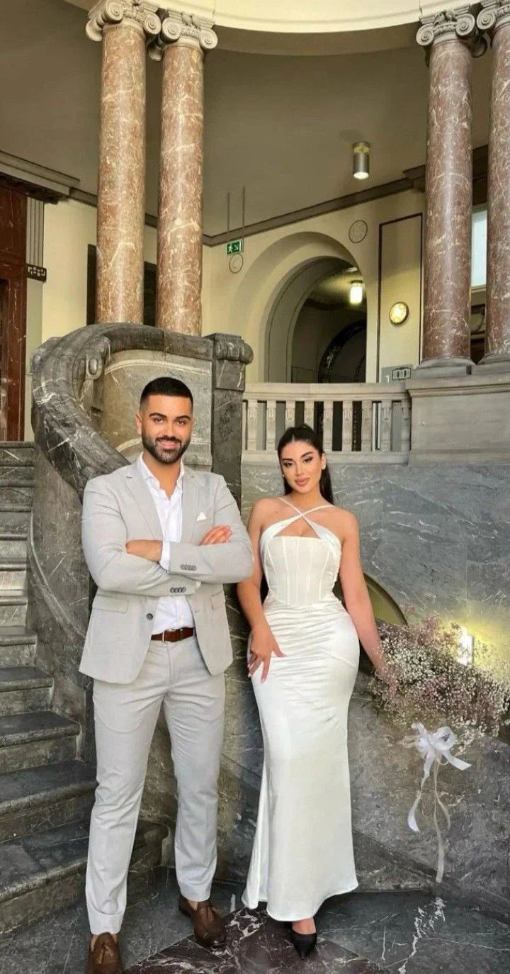 Elegant couple in formal attire poses on marble staircase, ZAPDRESS white gown, classic setting