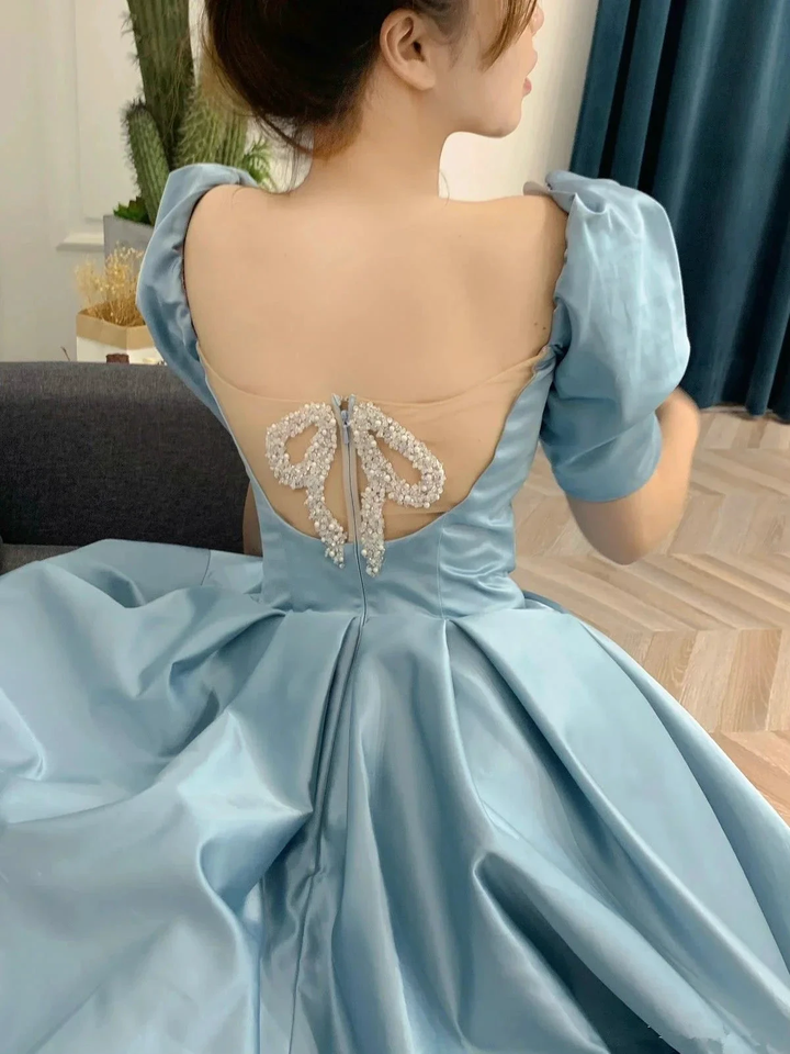 Woman in light blue satin dress with puff sleeves and pearl bow detail on the back, ZAPDRESS