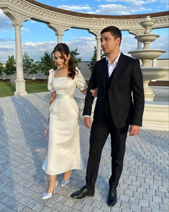 Elegant couple in formal attire walking outdoors near a white pavilion and fountain, ZAPDRESS style