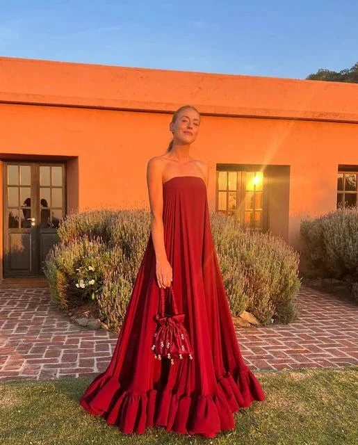 Woman in a strapless red maxi dress holding a matching bag, standing outside at sunset, ZAPDRESS