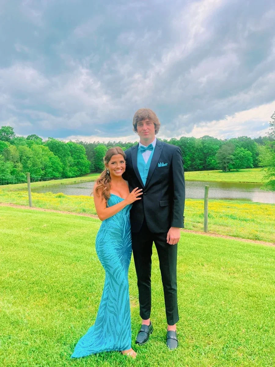 Couple in turquoise formal dress and tuxedo with ZAPDRESS style, posing outdoors by pond