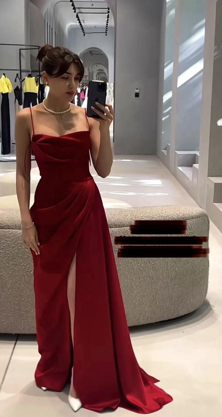 Woman in a red evening dress with spaghetti straps and thigh-high slit, in boutique setting