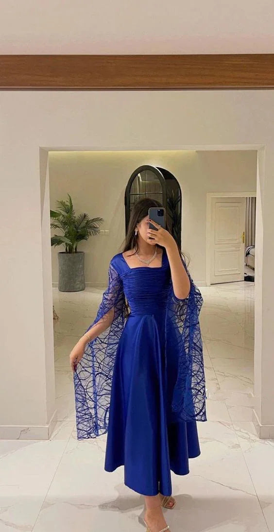 Woman in elegant royal blue dress with sheer sleeves in a modern, stylish room, ZAPDRESS fashion