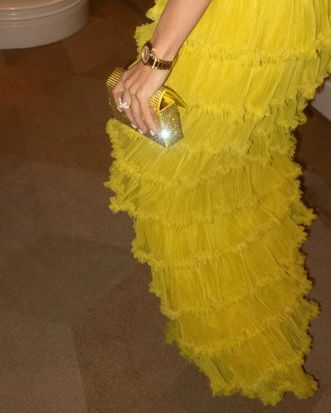 Woman in ruffled yellow dress holding gold clutch, elegant style by ZAPDRESS