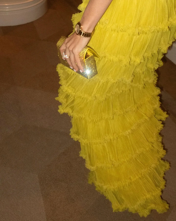 Woman in ruffled yellow dress holding gold clutch, elegant style by ZAPDRESS