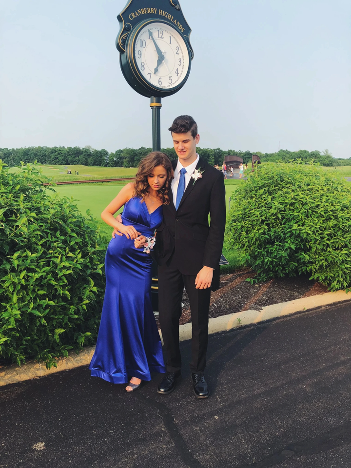 Couple in formal attire posing near Cranberry Highlands clock, elegant blue evening dress