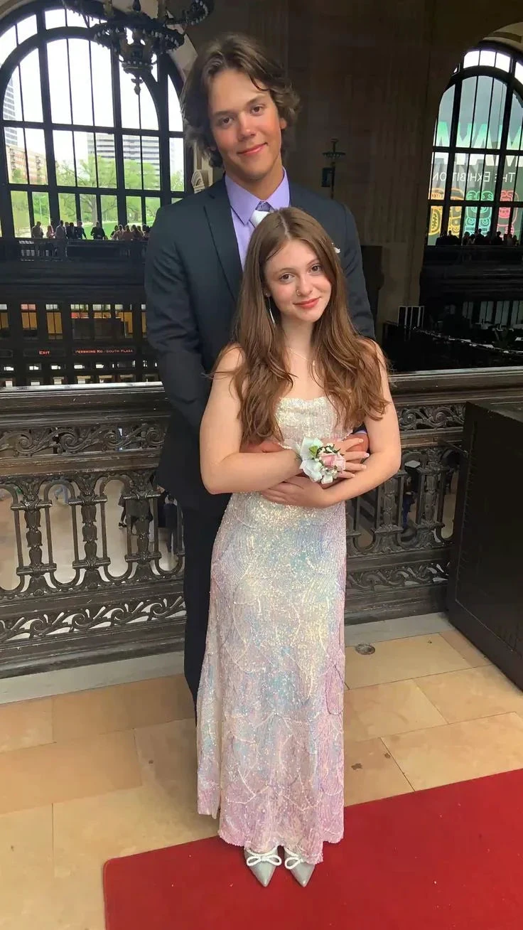 Young couple in formal attire posing at an elegant venue, woman in iridescent ZAPDRESS gown