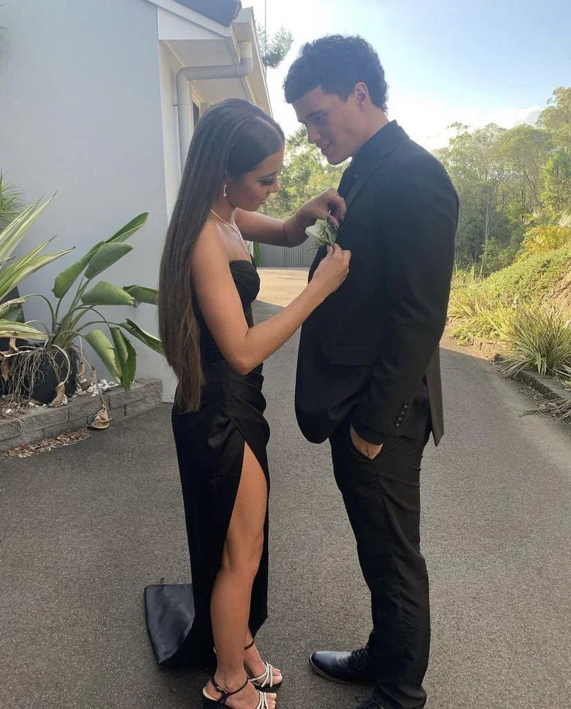 Young couple in formalwear, woman in black dress, man in suit, outdoors by house