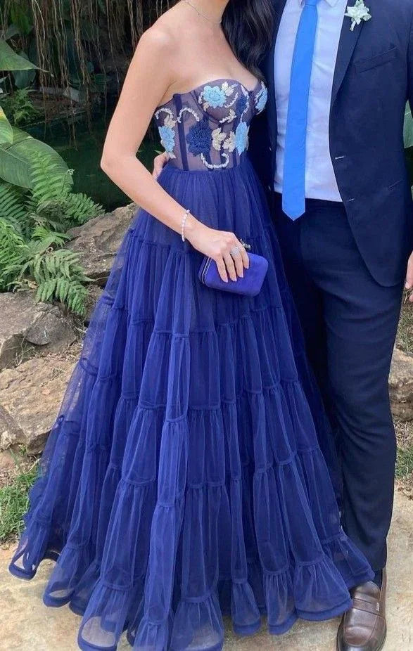Woman in strapless blue floral gown holding clutch, elegant formal dress from ZAPDRESS