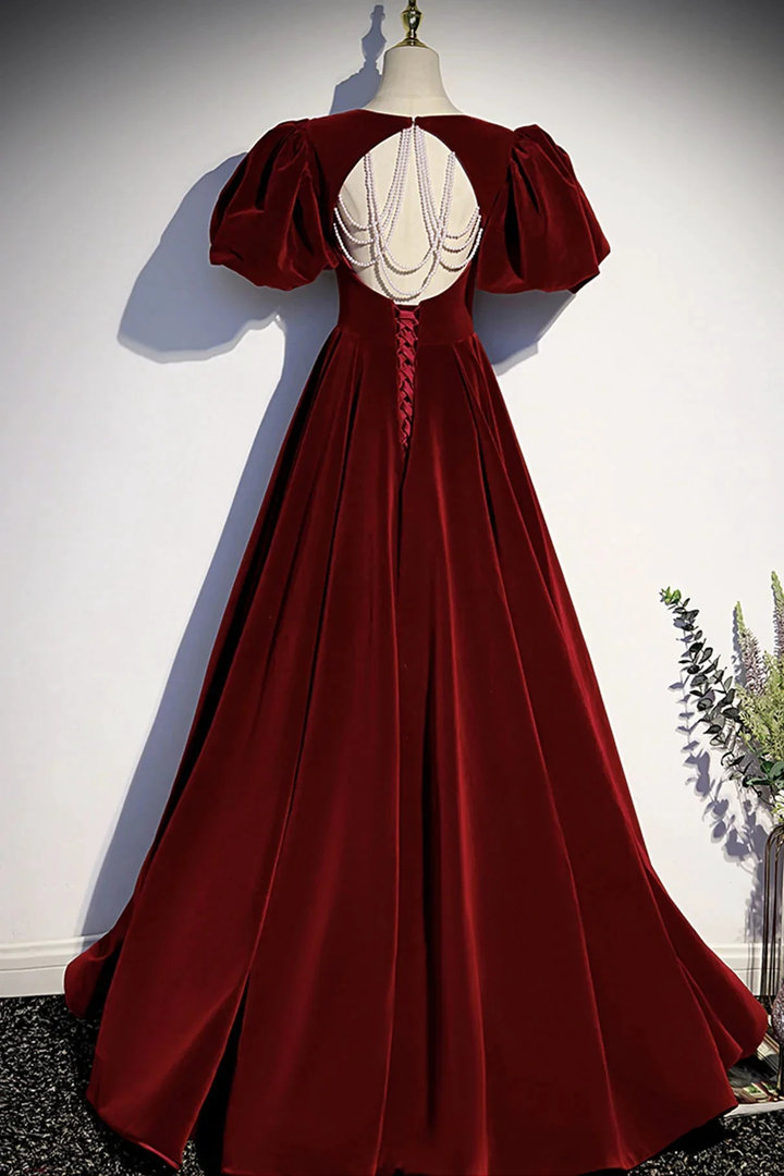 Elegant burgundy velvet evening gown with puff sleeves and pearl back details on mannequin
