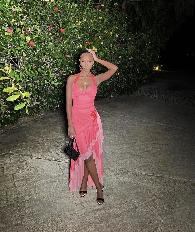 Woman in a pink ruffled dress poses outdoors at night with floral backdrop, ZAPDRESS fashion