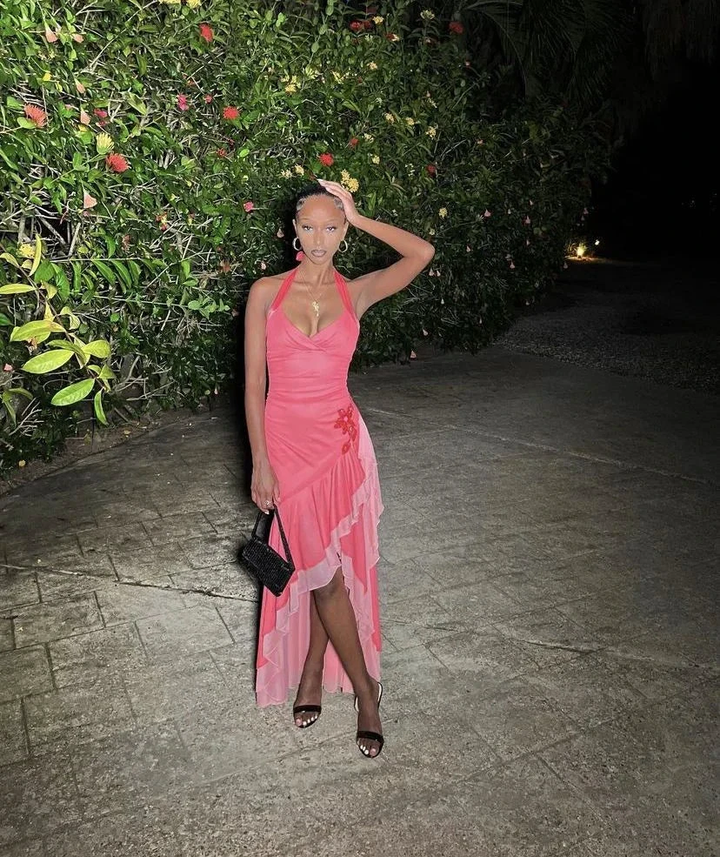 Woman in a pink ruffled dress poses outdoors at night with floral backdrop, ZAPDRESS fashion