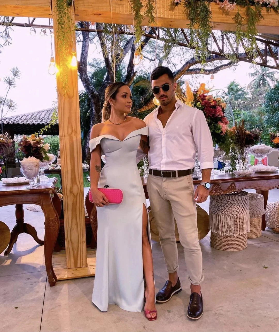 Elegant couple posing at event, woman in off-shoulder white dress, man in smart casual outfit, ZAPDRESS
