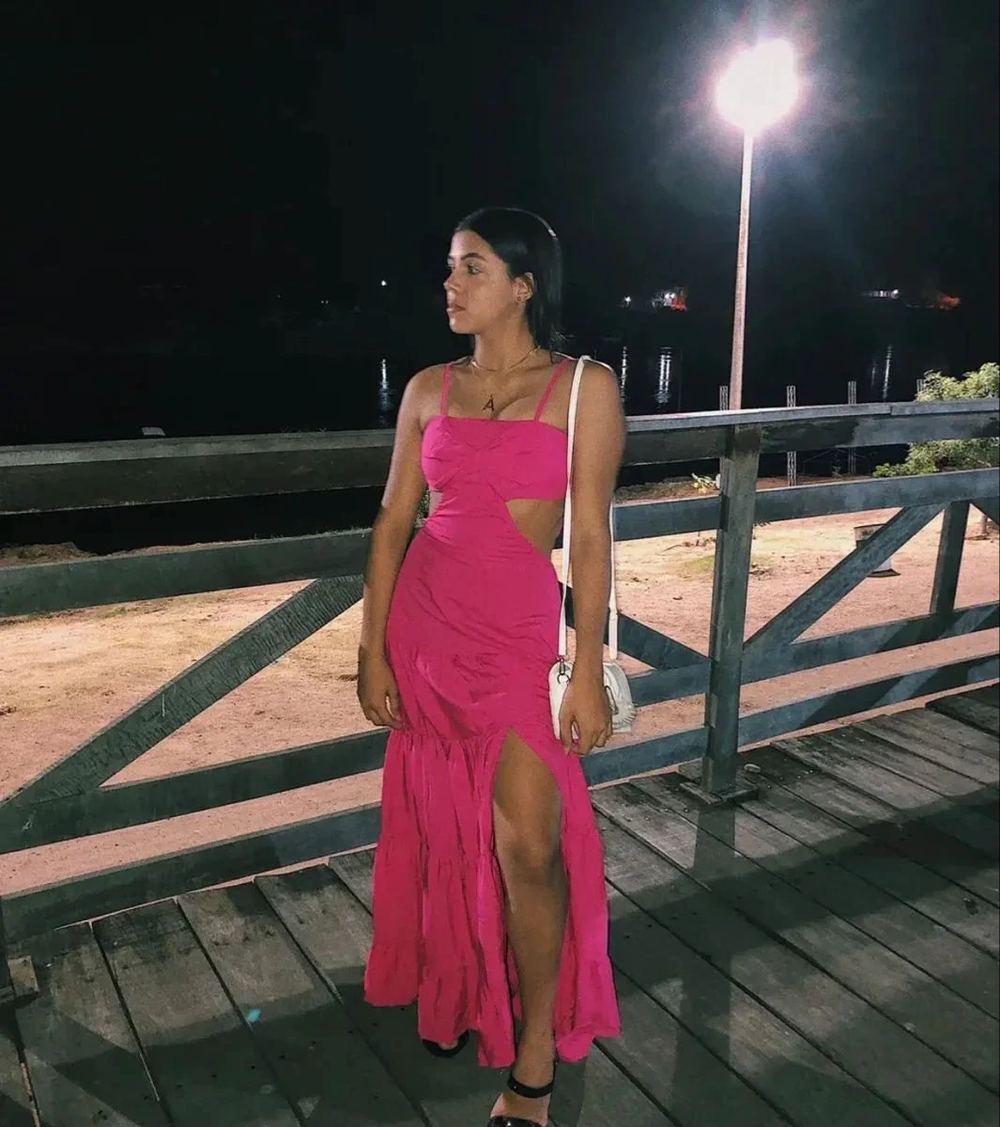 Woman wearing a vibrant pink cutout dress on a wooden deck at night, ZAPDRESS fashion