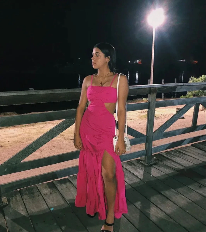 Woman wearing a vibrant pink cutout dress on a wooden deck at night, ZAPDRESS fashion