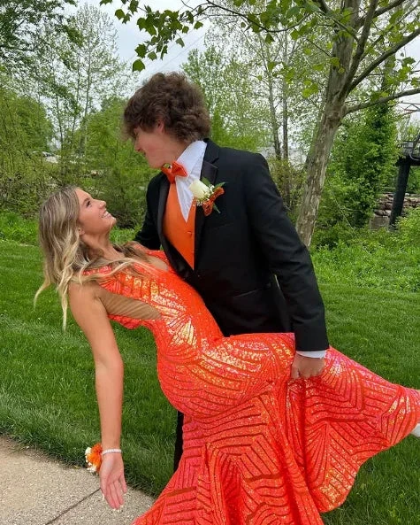 Young couple in formal attire, woman in sequined orange gown, posing outdoors, ZAPDRESS