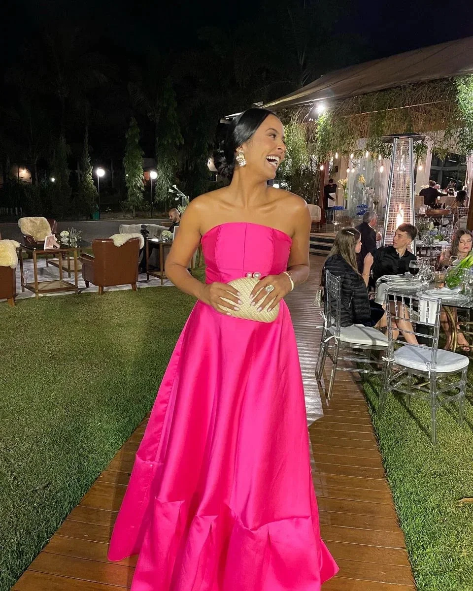 Woman in bright pink strapless evening gown holding clutch at elegant outdoor event, ZAPDRESS style