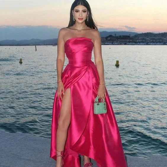Woman in vibrant pink satin strapless evening dress by the water at sunset, ZAPDRESS fashion