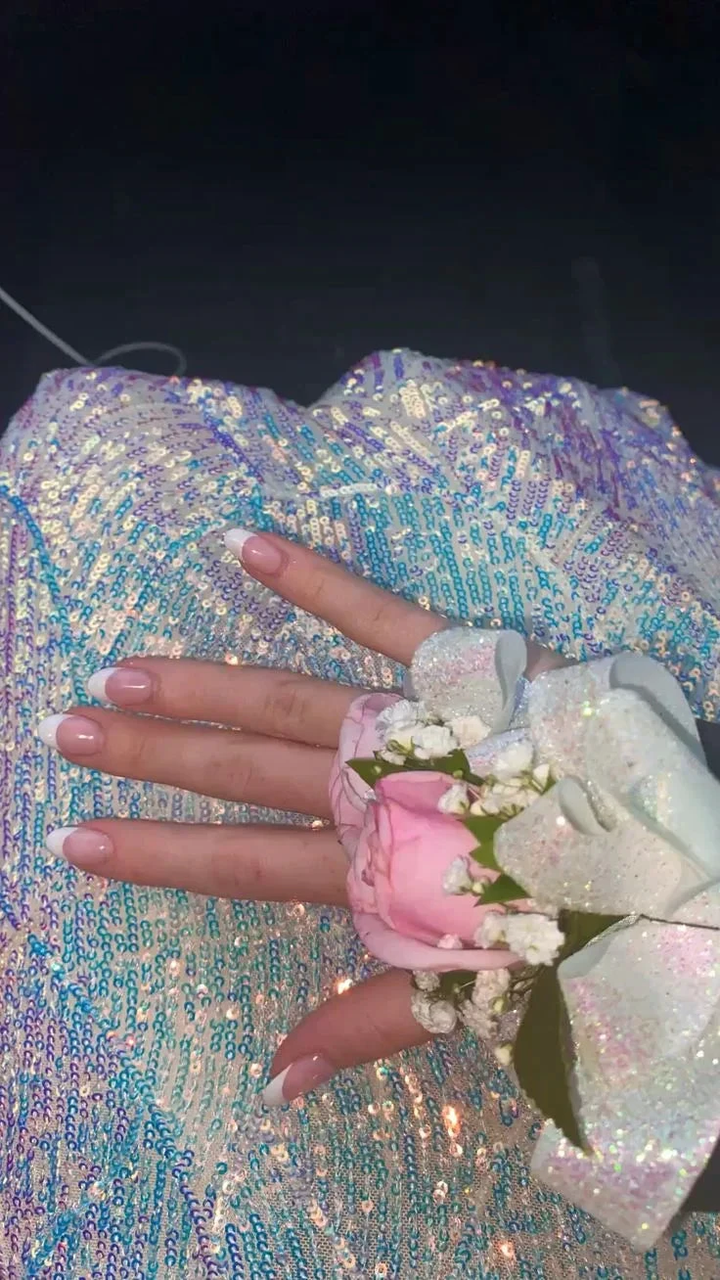 Hand with French manicure and pink corsage resting on a sparkling sequin ZAPDRESS gown