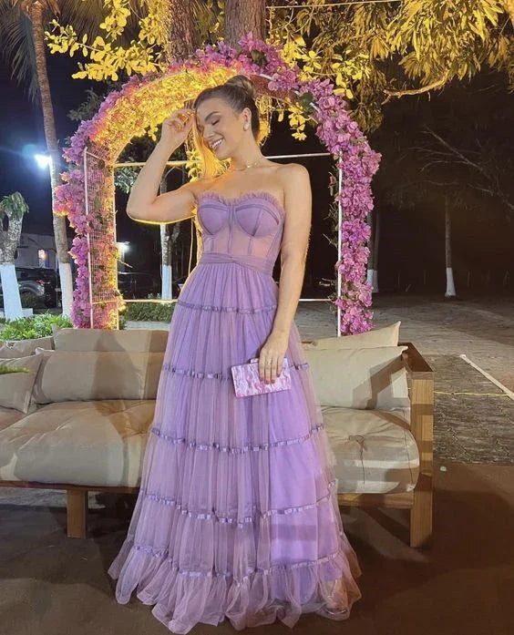 Woman in a lilac evening dress holding a clutch, standing by floral arch at night, ZAPDRESS