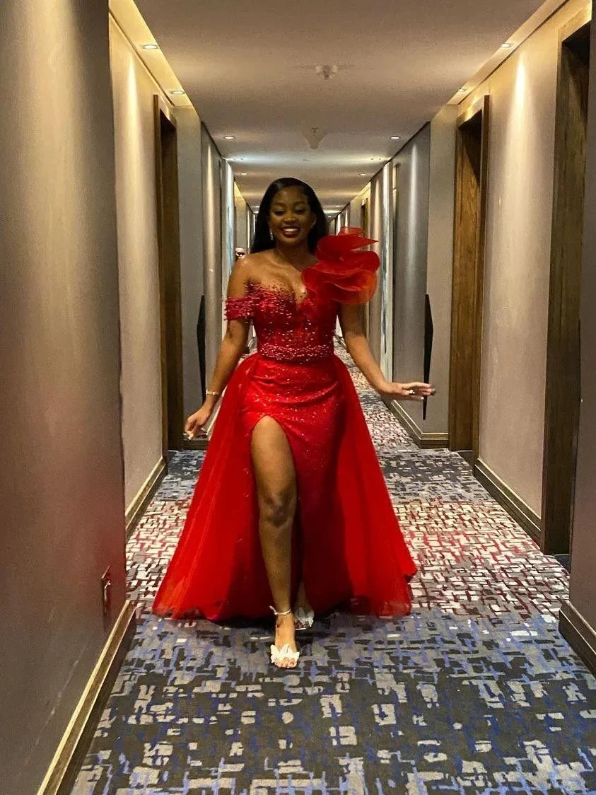 Woman in a glamorous red evening gown with floral embellishment at ZAPDRESS, walking in a hallway