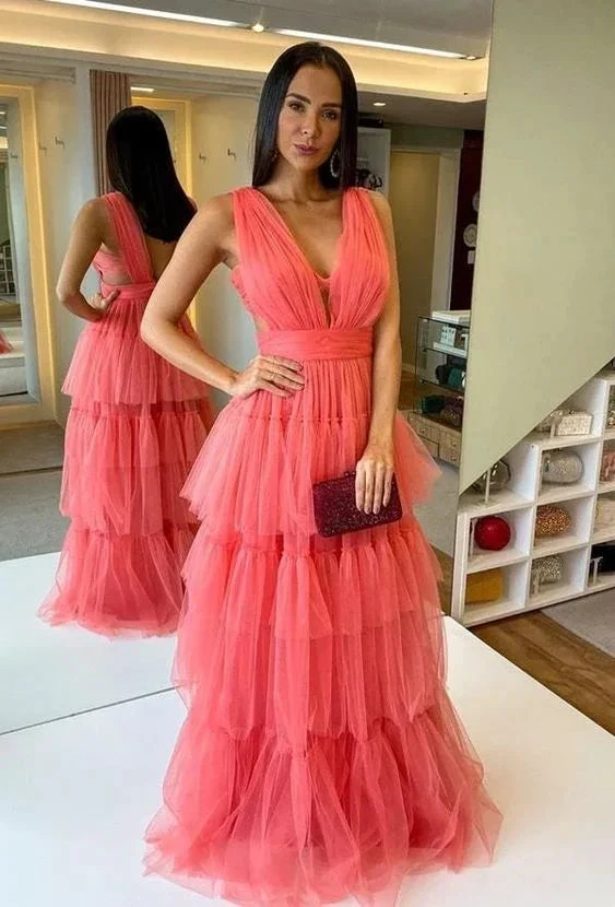 Woman in coral pink tiered tulle evening gown holding clutch in boutique fitting room, ZAPDRESS
