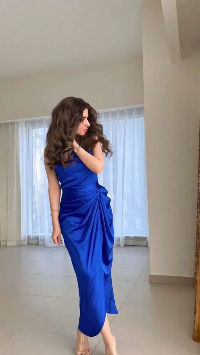 Woman wearing a vibrant blue satin dress in a modern, minimalist room for ZAPDRESS