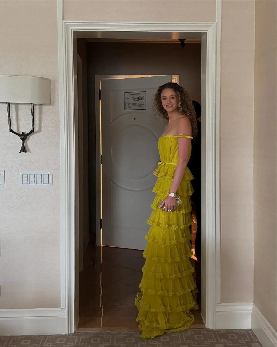 Woman in a bright yellow ruffled evening gown standing in a doorway, Zapdress fashion.