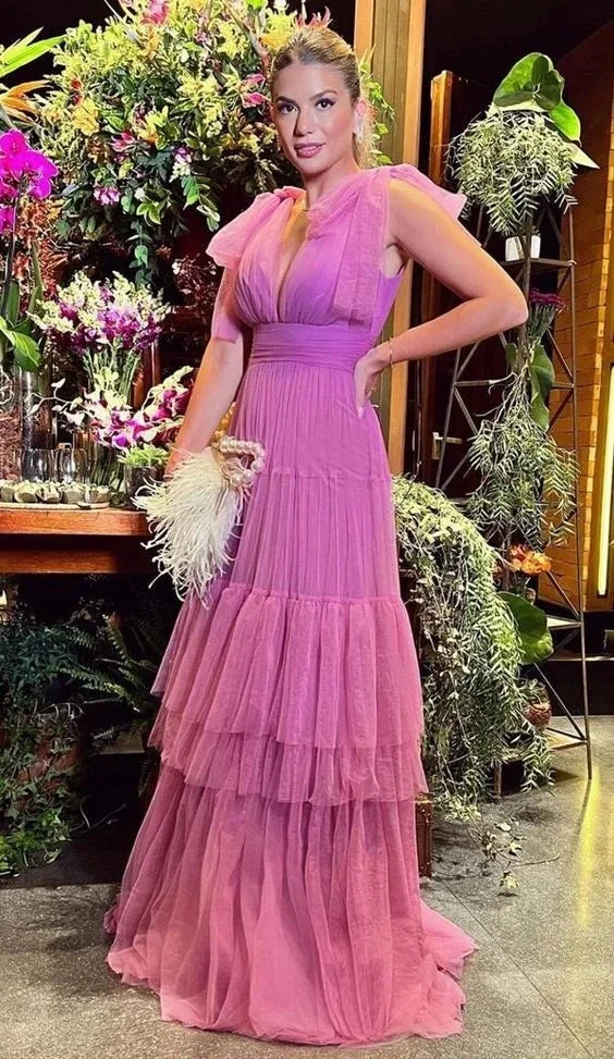 Woman in a tiered pink evening gown posing indoors with lush floral background, ZAPDRESS