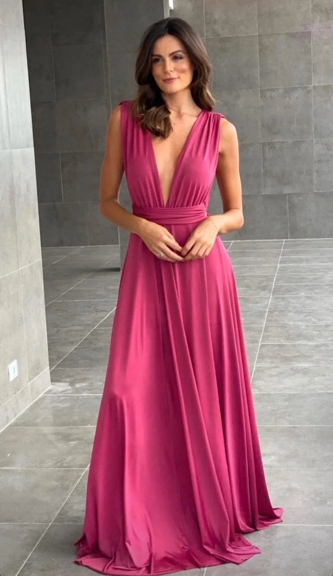 Woman wearing a deep V-neck pink maxi dress from ZAPDRESS in a modern tile interior