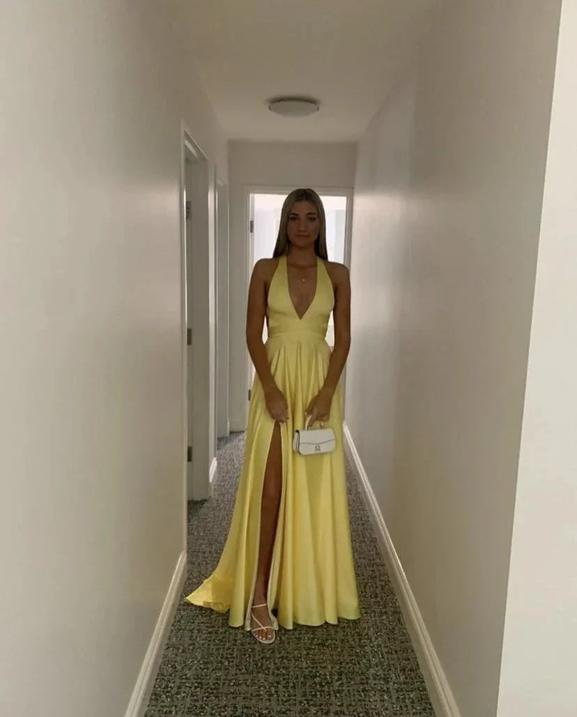 Woman in a long yellow evening dress with side slit, holding a white purse, ZAPDRESS fashion