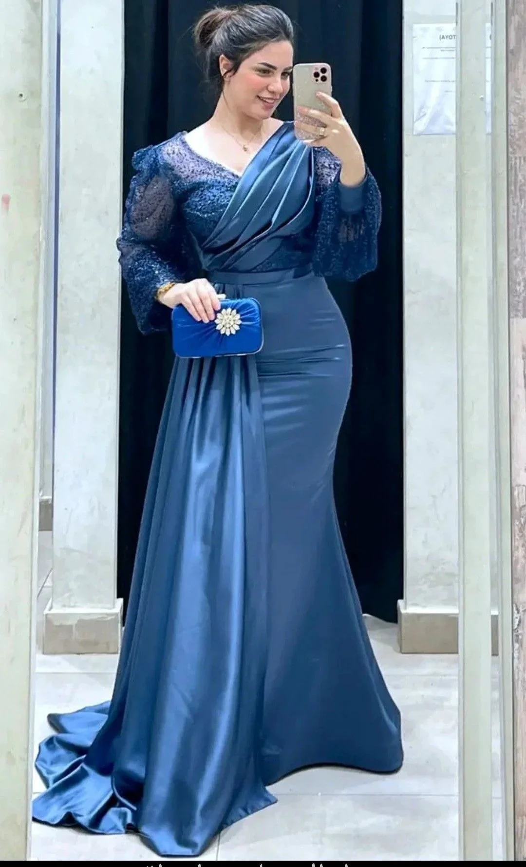 Woman in a blue evening gown with lace sleeves holding a matching clutch, ZAPDRESS fashion